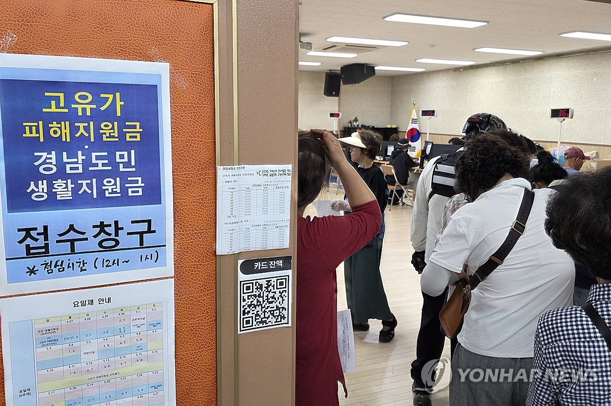 고유가 지원금 신청 첫날, 주민센터 앞에 줄선 시민과 안내 표지판이 보이는 현장 사진