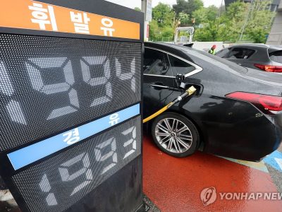 주유소 가격표 옆에서 연료 가격이 오르는 장면