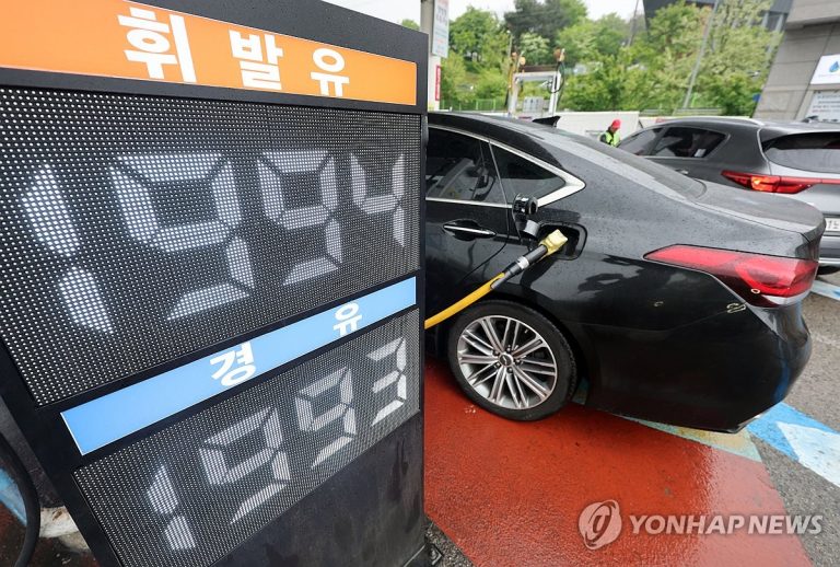 주유소 가격표 옆에서 연료 가격이 오르는 장면
